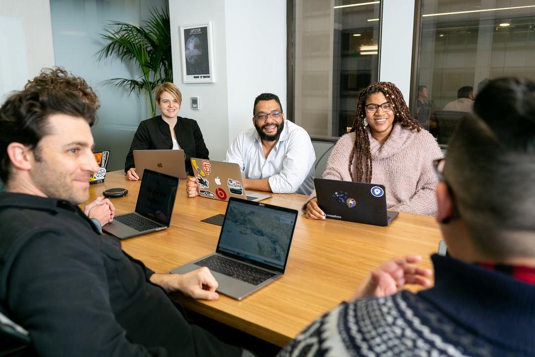 A group of people sitting at a desk in a meeting.